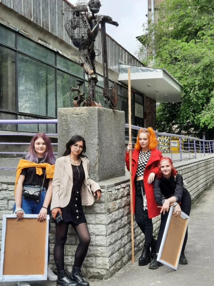 Students with drawings outside an academic building