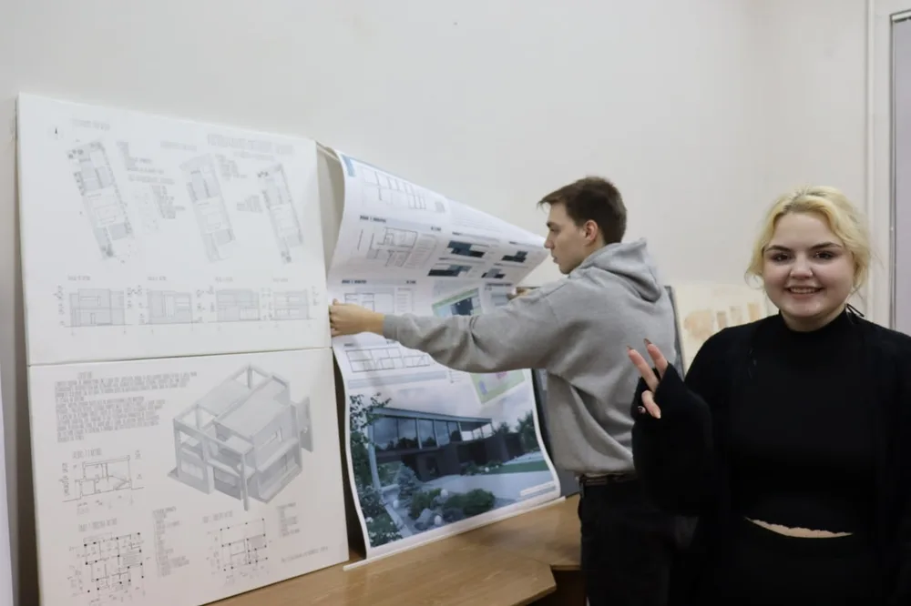 A teacher and student beside architectural drawings