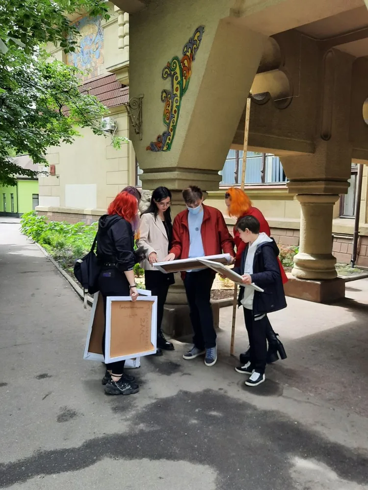 Students carrying drawings outside an academic building