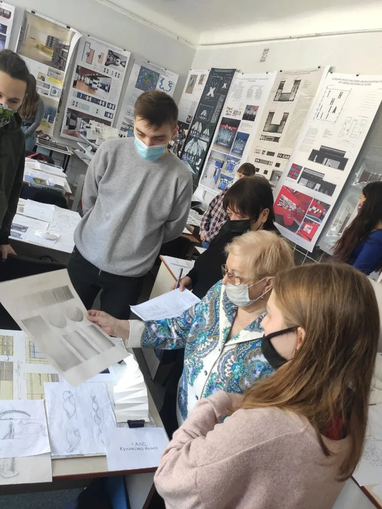 A teacher discussing drawings with a student